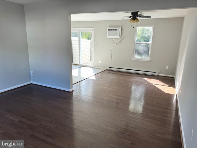 empty room with ceiling fan, baseboard heating, a wealth of natural light, and dark wood-type flooring