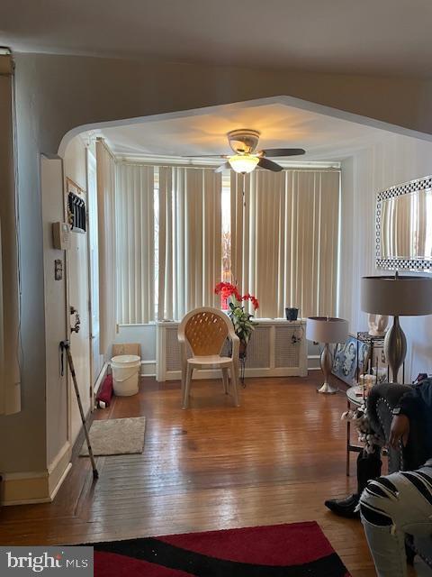 living area featuring wood-type flooring and ceiling fan