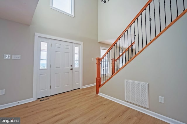 entryway with a towering ceiling and light hardwood / wood-style floors