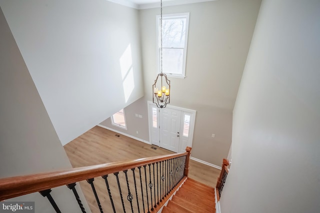 staircase with wood-type flooring and an inviting chandelier