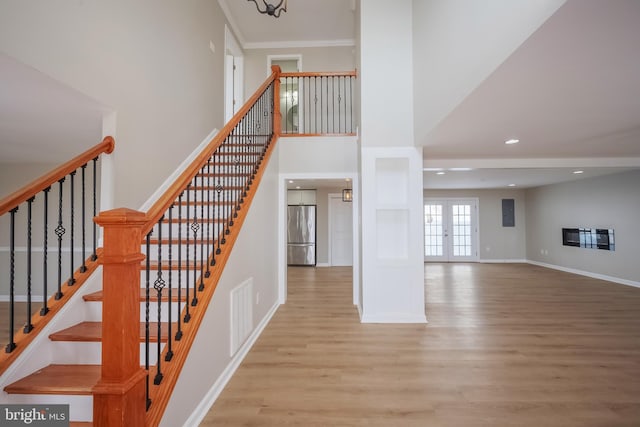 stairs with hardwood / wood-style floors, an inviting chandelier, and french doors