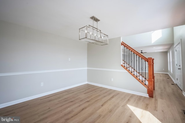 unfurnished dining area with light hardwood / wood-style floors and ceiling fan with notable chandelier