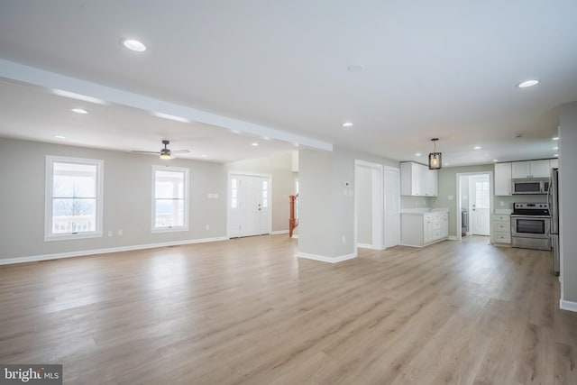 unfurnished living room featuring beam ceiling, light hardwood / wood-style flooring, and ceiling fan