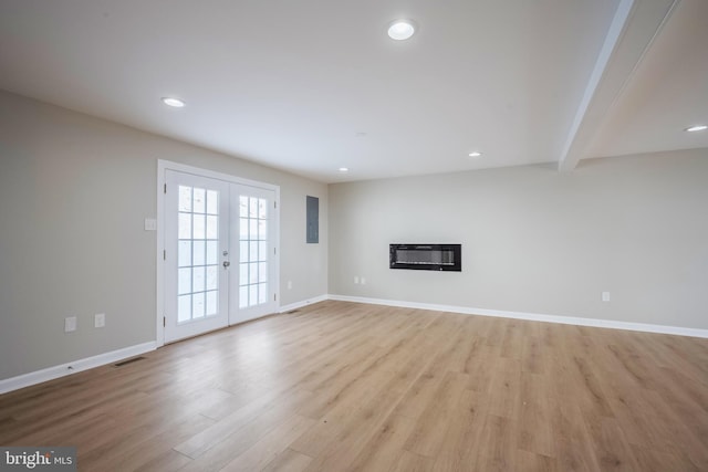 unfurnished living room with beamed ceiling, french doors, and light wood-type flooring