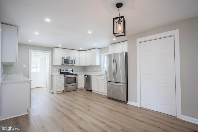 kitchen featuring sink, light hardwood / wood-style flooring, decorative light fixtures, white cabinetry, and stainless steel appliances