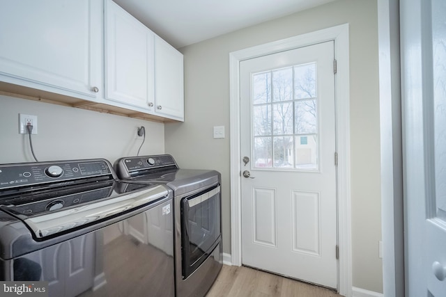 washroom with washer and clothes dryer, cabinets, and light wood-type flooring