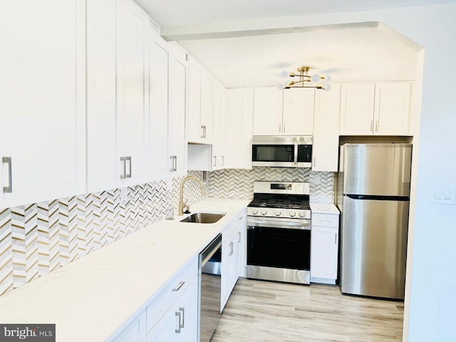 kitchen with white cabinetry, sink, light stone countertops, and appliances with stainless steel finishes