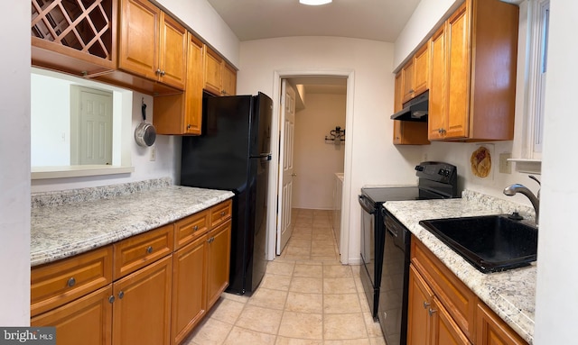 kitchen with light stone counters, black appliances, and sink