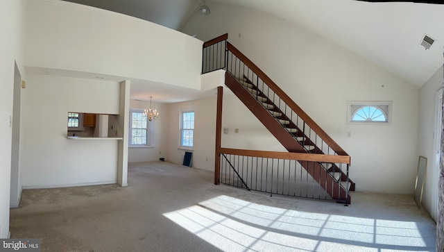 stairs with carpet flooring, high vaulted ceiling, and a chandelier