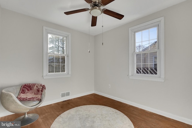 sitting room with visible vents, wood finished floors, baseboards, and ceiling fan