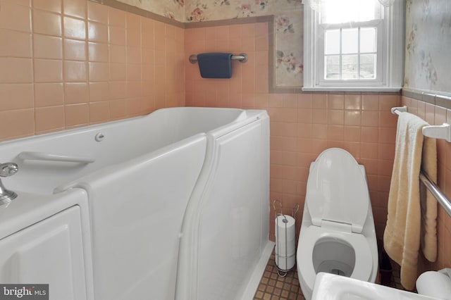 full bathroom featuring toilet, tile walls, wainscoting, and wallpapered walls