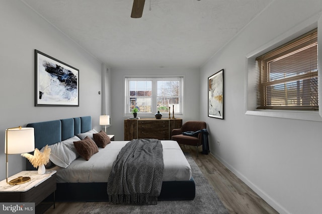 bedroom with a ceiling fan, wood finished floors, and baseboards