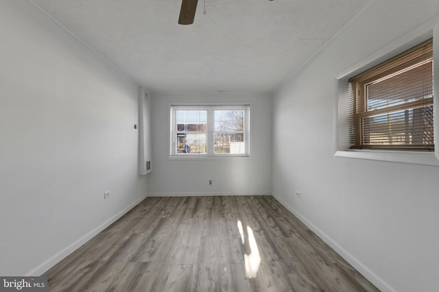 empty room featuring baseboards, wood finished floors, and a ceiling fan