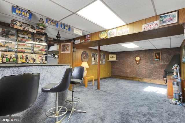 bar with carpet floors, a paneled ceiling, and wood walls