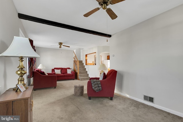 carpeted living room with visible vents, beamed ceiling, arched walkways, baseboards, and stairs