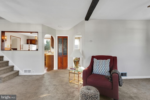 living area with carpet, baseboards, visible vents, arched walkways, and stairs