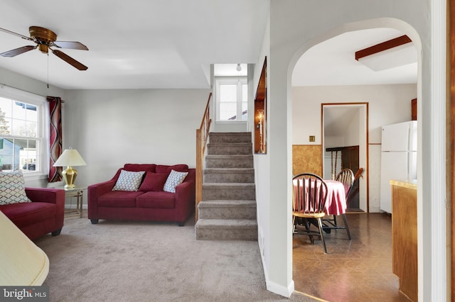 living area featuring stairs, a healthy amount of sunlight, arched walkways, and carpet floors