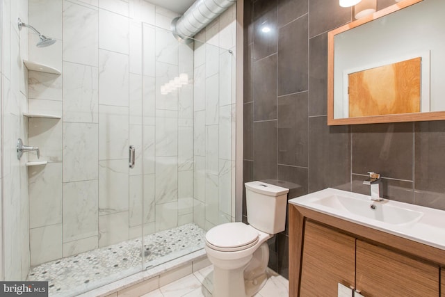 bathroom with vanity, toilet, tile walls, and a shower with shower door