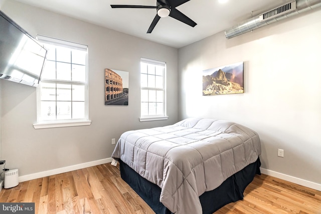 bedroom featuring ceiling fan, wood-type flooring, and multiple windows