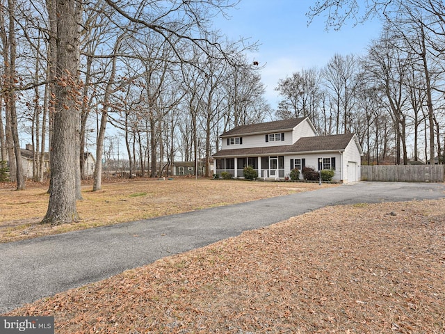 view of property featuring covered porch, a front lawn, and a garage