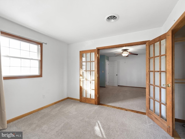 carpeted empty room with ceiling fan and french doors