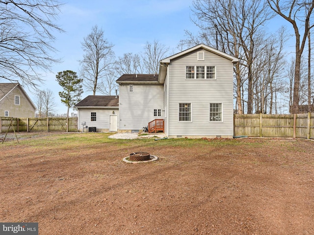 rear view of property featuring a fire pit, central AC, and a lawn