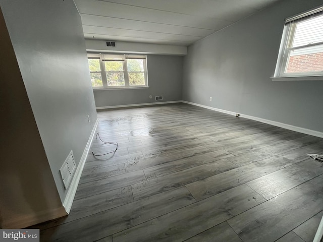 spare room with plenty of natural light and dark wood-type flooring