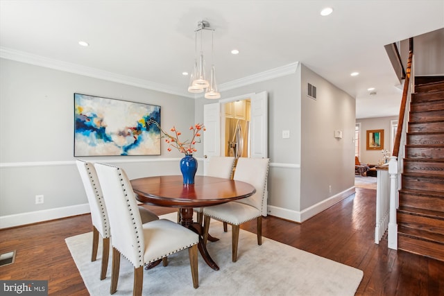 dining area with ornamental molding and dark hardwood / wood-style floors