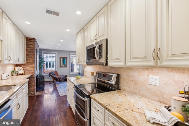 kitchen featuring appliances with stainless steel finishes, dark hardwood / wood-style floors, white cabinets, and light stone counters