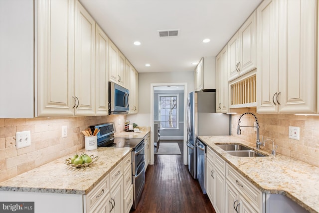 kitchen featuring sink, dark wood-type flooring, stainless steel appliances, light stone counters, and decorative backsplash