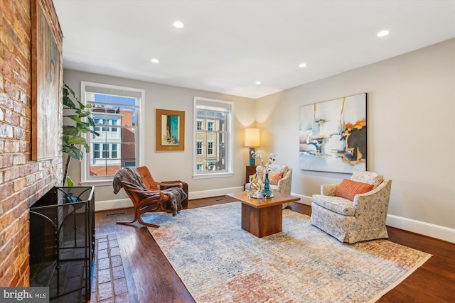 living area featuring a brick fireplace and dark hardwood / wood-style floors