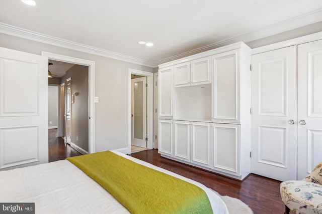 bedroom featuring dark hardwood / wood-style flooring, ornamental molding, and a closet