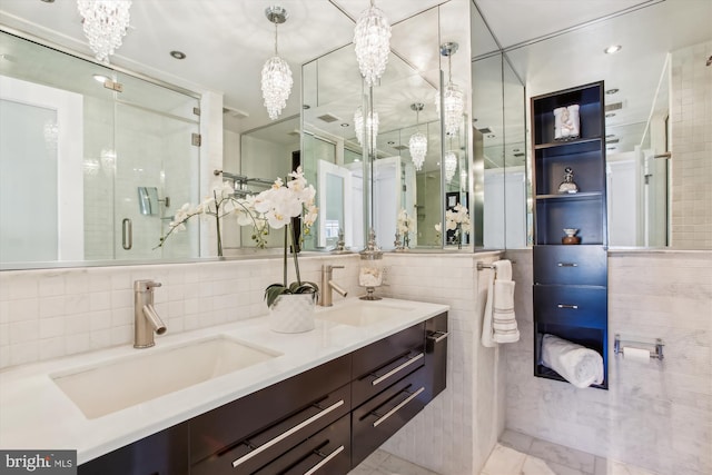 bathroom with vanity, a shower with shower door, and tile walls