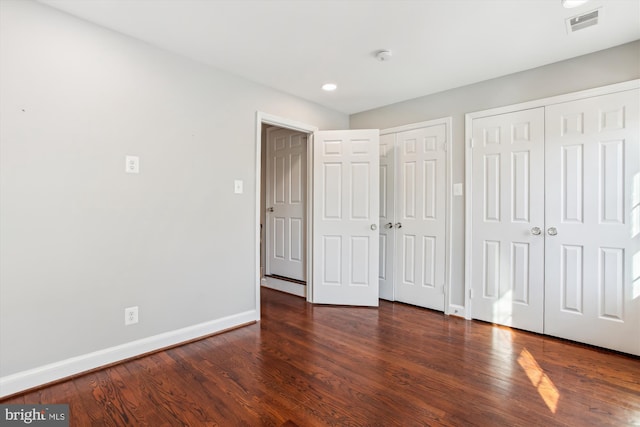 unfurnished bedroom with dark hardwood / wood-style flooring and two closets