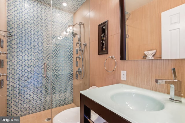 bathroom with vanity, toilet, tile walls, and walk in shower