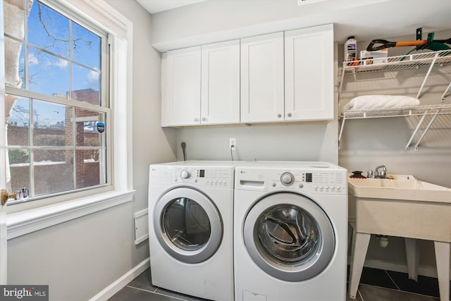 laundry area with cabinets, a healthy amount of sunlight, separate washer and dryer, and dark tile patterned floors