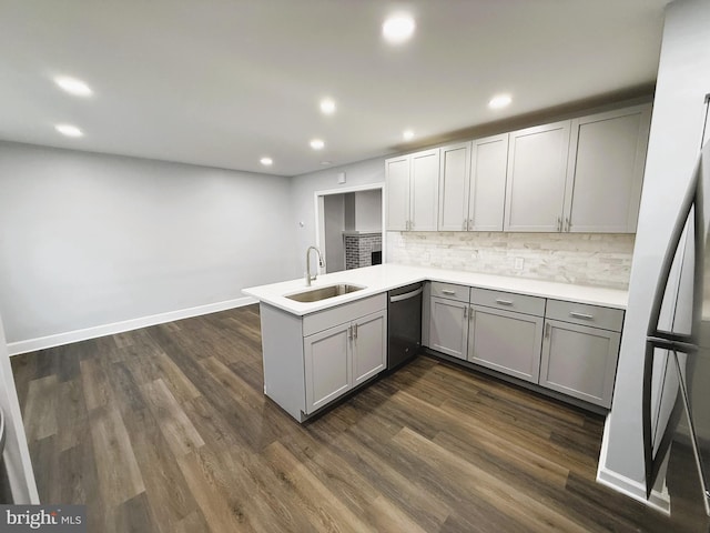 kitchen featuring stainless steel dishwasher, kitchen peninsula, decorative backsplash, sink, and gray cabinetry