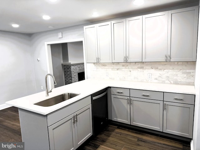 kitchen with sink, black dishwasher, dark hardwood / wood-style floors, and kitchen peninsula