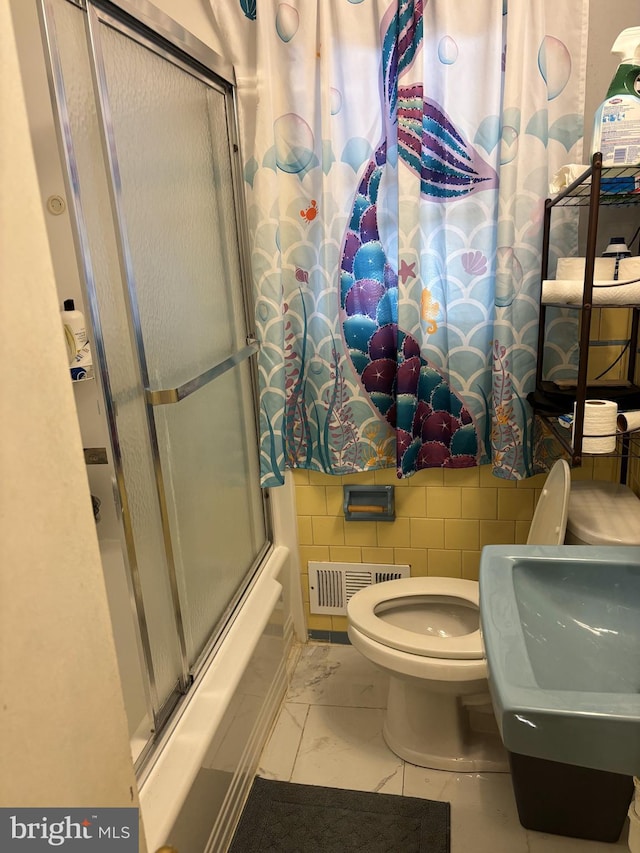 full bathroom featuring toilet, bath / shower combo with glass door, sink, and decorative backsplash