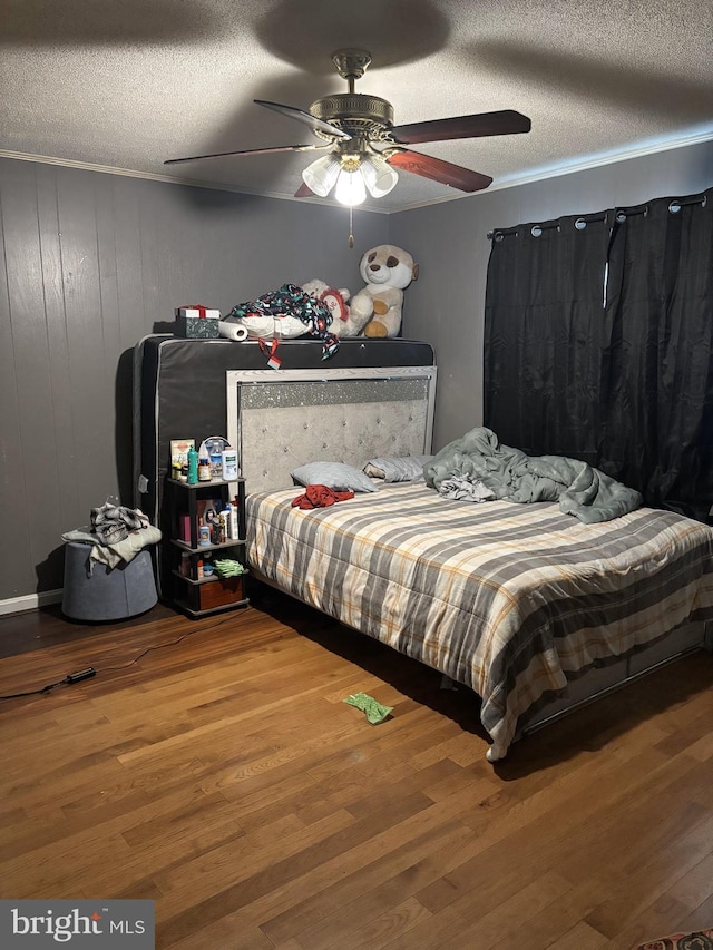 bedroom featuring hardwood / wood-style flooring, ceiling fan, wooden walls, and a textured ceiling