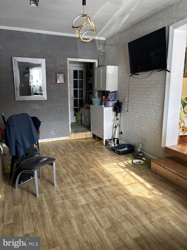 living area with ornamental molding, brick wall, and light hardwood / wood-style floors