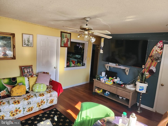 living room featuring ceiling fan, dark hardwood / wood-style floors, and a textured ceiling