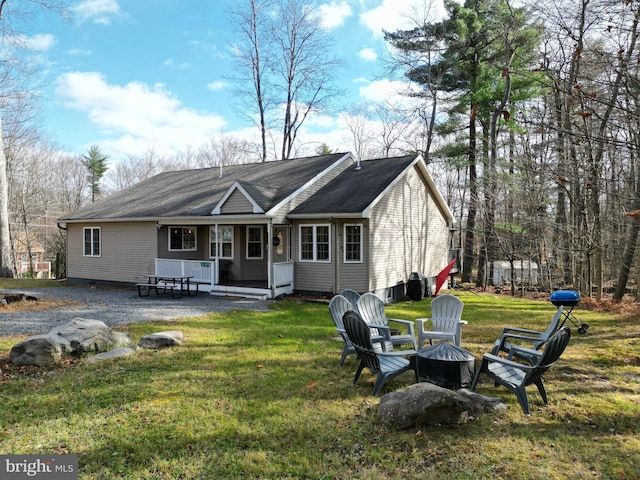 rear view of property with a yard and a fire pit