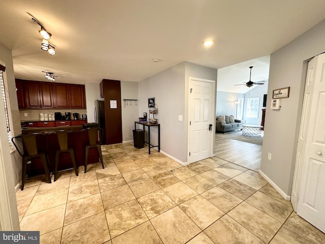 kitchen with ceiling fan, rail lighting, stainless steel fridge, a breakfast bar area, and light tile patterned floors