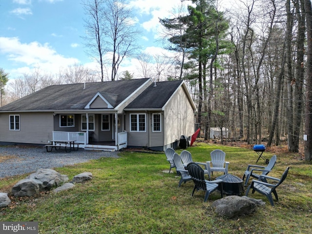 back of house featuring a fire pit, covered porch, and a yard