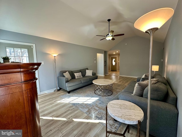 living room featuring ceiling fan, light hardwood / wood-style floors, and vaulted ceiling