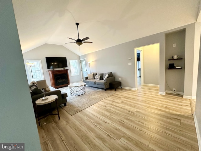 living room featuring ceiling fan, lofted ceiling, and light wood-type flooring