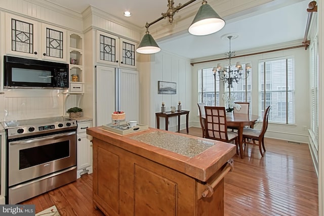 kitchen with stainless steel range with electric stovetop, crown molding, light wood-type flooring, decorative light fixtures, and a chandelier