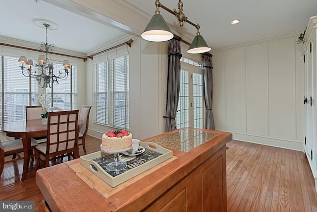 dining space featuring a notable chandelier, ornamental molding, and light hardwood / wood-style flooring