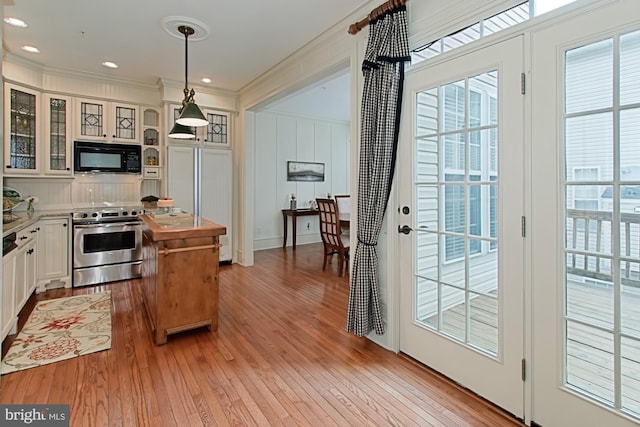 kitchen featuring crown molding, light hardwood / wood-style flooring, stainless steel range oven, white cabinetry, and hanging light fixtures